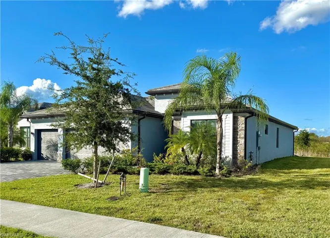 View of front facade with a front lawn, an attached garage, and decorative driveway