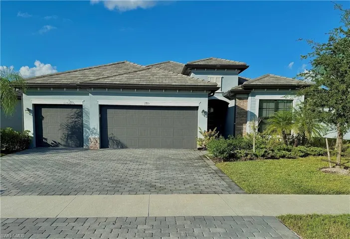 Prairie-style house with an attached garage, decorative driveway, a tile roof, and stucco siding