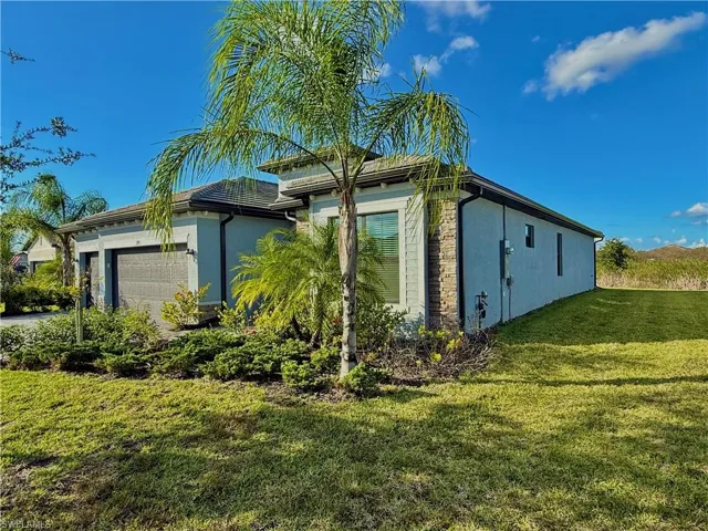 View of home's exterior with stucco siding, a yard, and a garage