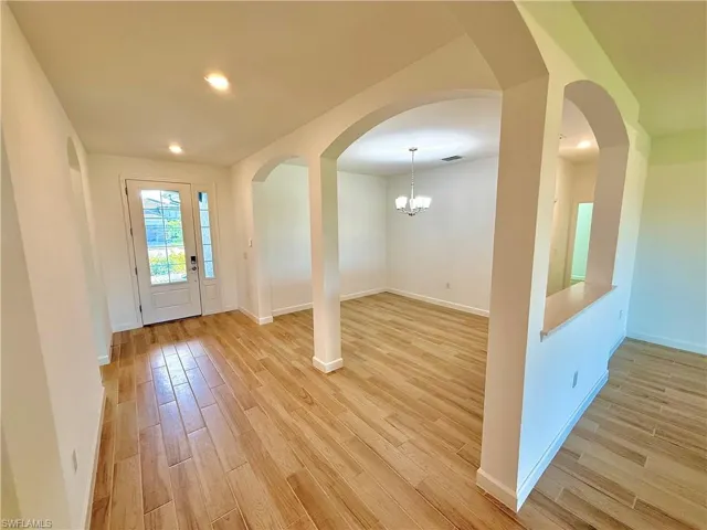 Foyer entrance with a chandelier, light wood-type flooring, recessed lighting, and arched walkways