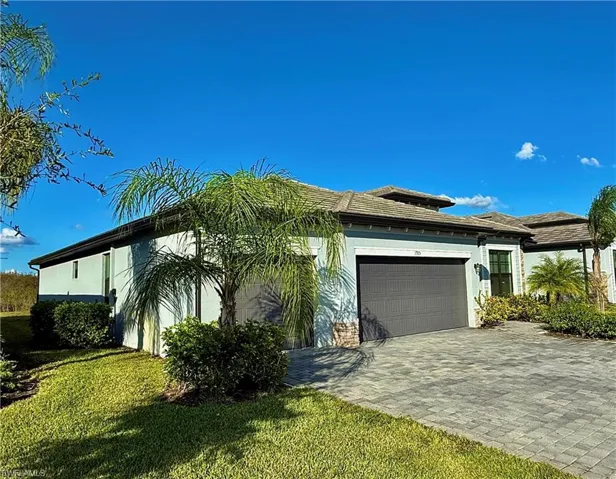 View of front facade featuring stucco siding, a garage, decorative driveway, a front lawn, and a tiled roof