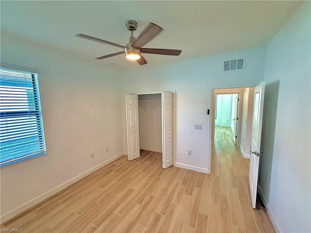 Unfurnished bedroom with ceiling fan, light wood-style floors, and a closet