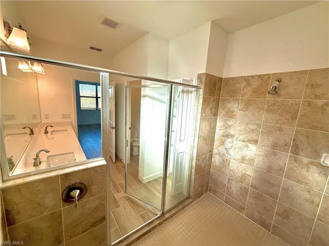 Full bath with double vanity and a stall shower
