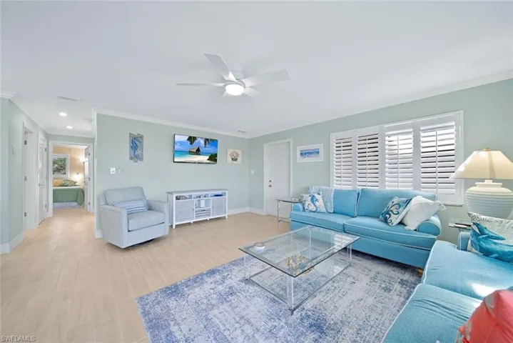 Living room with crown molding, light wood finished floors, healthy amount of natural light, and a ceiling fan