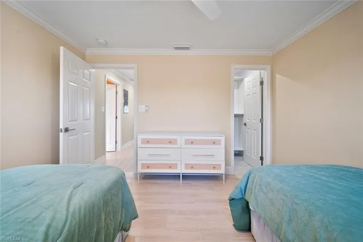 Bedroom with crown molding, light wood-style floors, and a ceiling fan