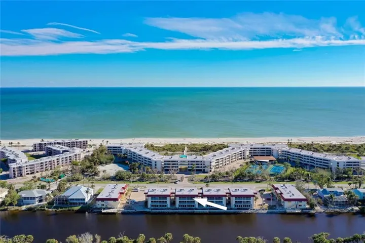 Bird's eye view of apartment complex and waterfront with a beach