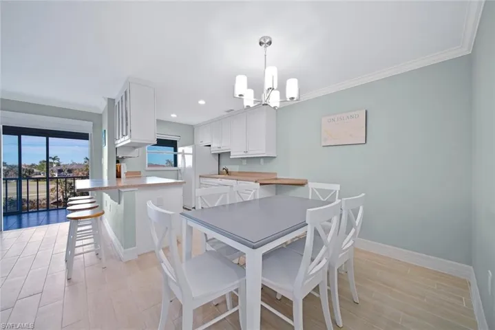 Dining room featuring wood finish floors, ornamental molding, a chandelier, and recessed lighting