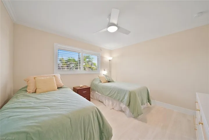 Bedroom featuring ornamental molding, light wood-style flooring, and a ceiling fan