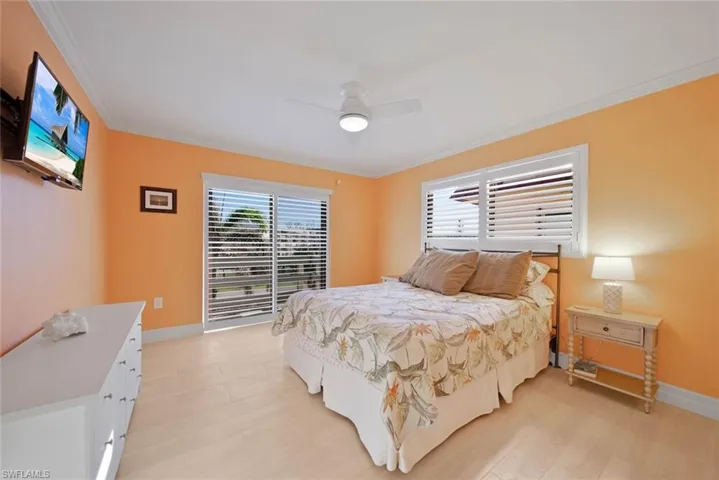 Bedroom with multiple windows, crown molding, a ceiling fan, and light wood-style flooring