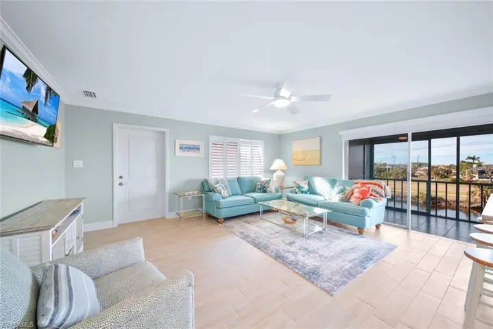 Living room with ornamental molding, light wood-style flooring, and ceiling fan