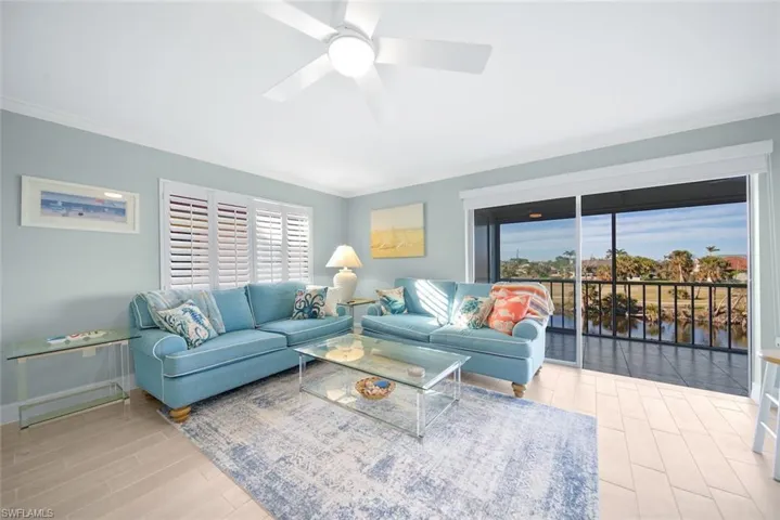 Living area with crown molding, wood finish floors, a ceiling fan, and a water view