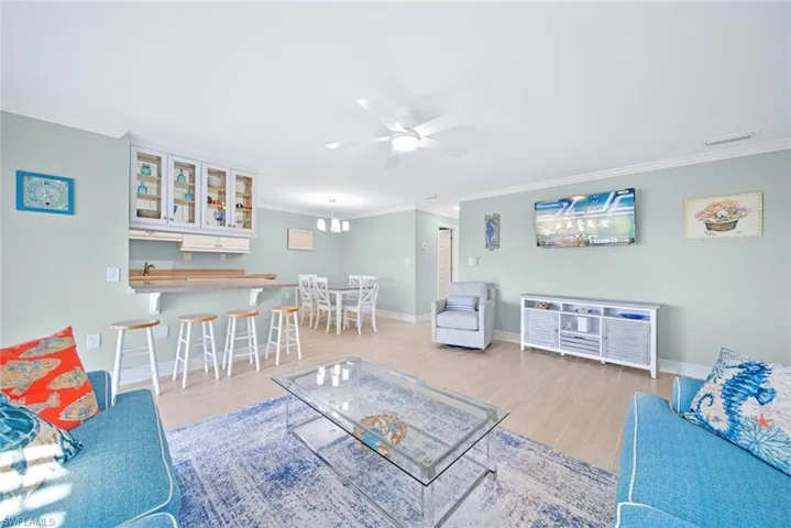 Living area featuring light wood finished floors, ceiling fan, and crown molding