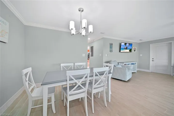 Dining room featuring light wood-type flooring, crown molding, and a chandelier