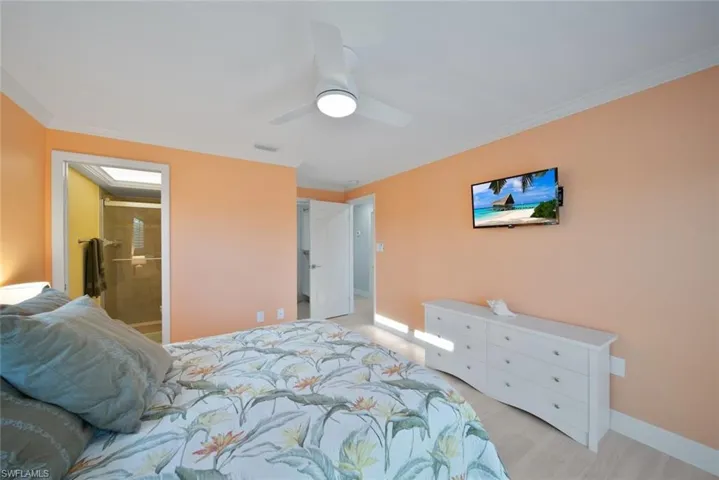Bedroom with ornamental molding, light wood-style floors, ceiling fan, and ensuite bathroom