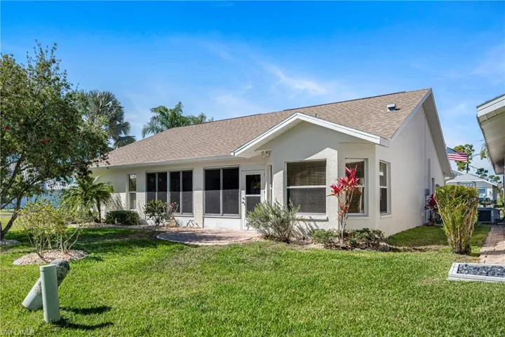 Rear view of house with roof with shingles, a yard, a sunroom, and stucco siding