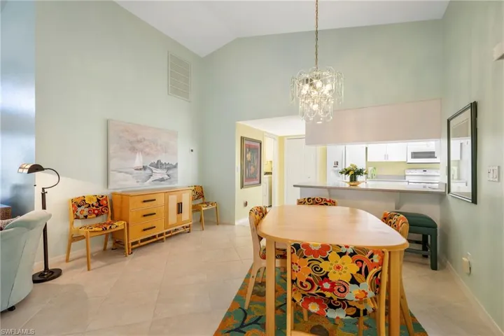 Dining room featuring vaulted ceiling, light tile patterned flooring, and a chandelier