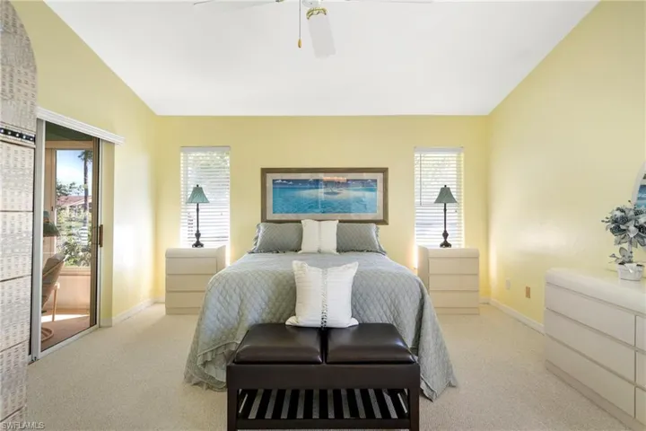 Bedroom featuring vaulted ceiling, access to outside, light carpet, and ceiling fan