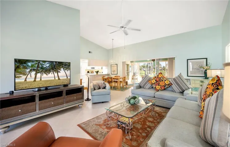 Living area featuring vaulted ceiling, a ceiling fan, and tile patterned floors