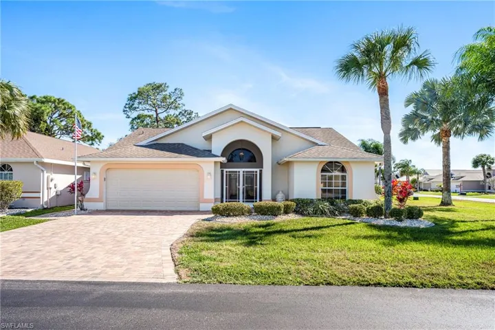 Single story home featuring a garage, decorative driveway, stucco siding, and a front lawn