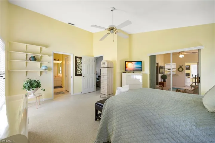 Bedroom featuring carpet flooring, a high ceiling, a ceiling fan, and ensuite bath