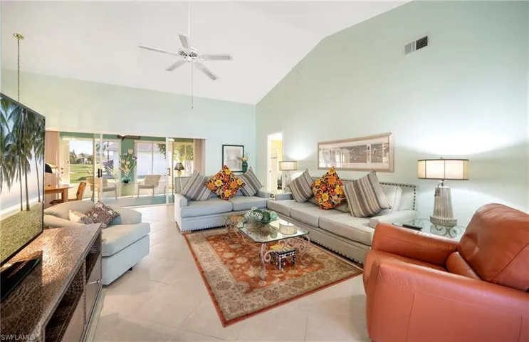 Living room featuring light tile patterned flooring, lofted ceiling, and ceiling fan