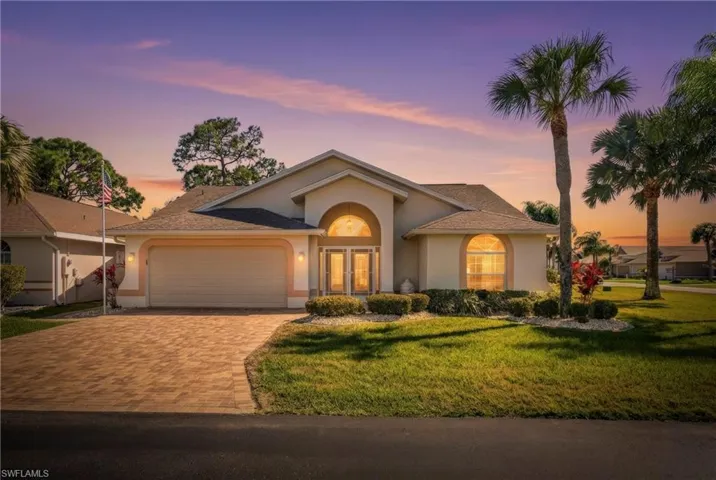 View of front of home with an attached garage, driveway, stucco siding, and a front lawn