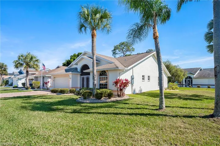 Single story home featuring a front lawn, an attached garage, and stucco siding