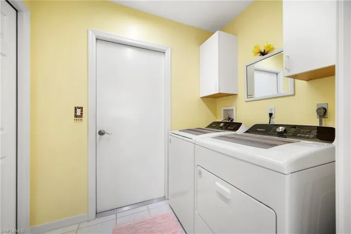 Laundry room featuring cabinet space, washing machine and clothes dryer, and light tile patterned floors