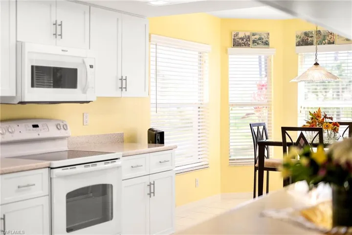 Kitchen with white appliances, white cabinetry, pendant lighting, and light tile patterned floors