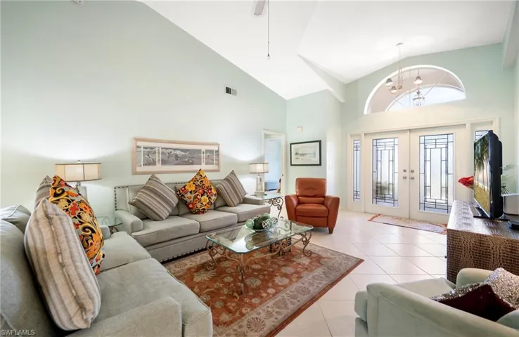 Living area featuring french doors, tile patterned flooring, suspended lighting, and lofted ceiling