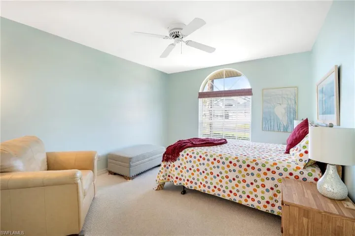 Carpeted bedroom with ceiling fan and baseboards