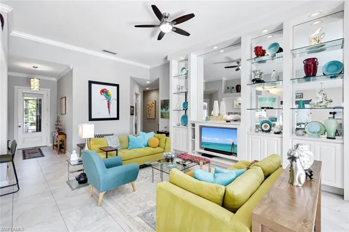 Living area featuring integrated built-in shelving with glass shelves and recessed lighting