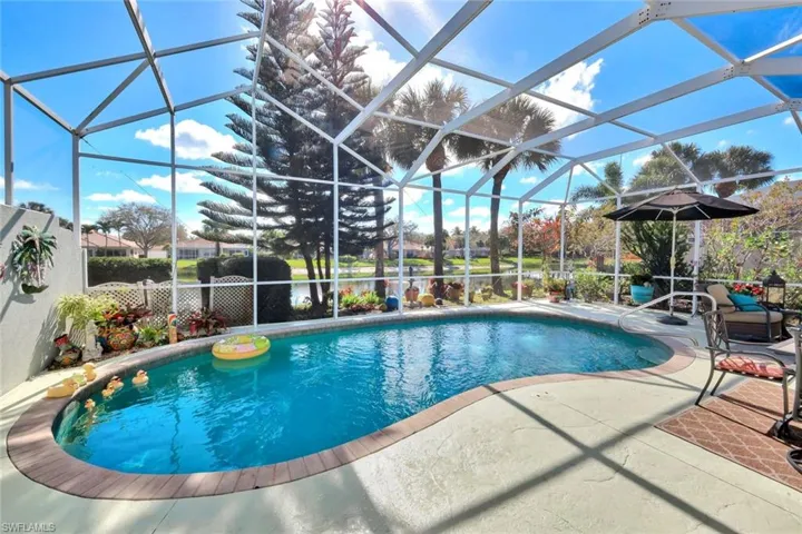 Screened-in pool enclosure featuring a freeform swimming pool with a hardscape border