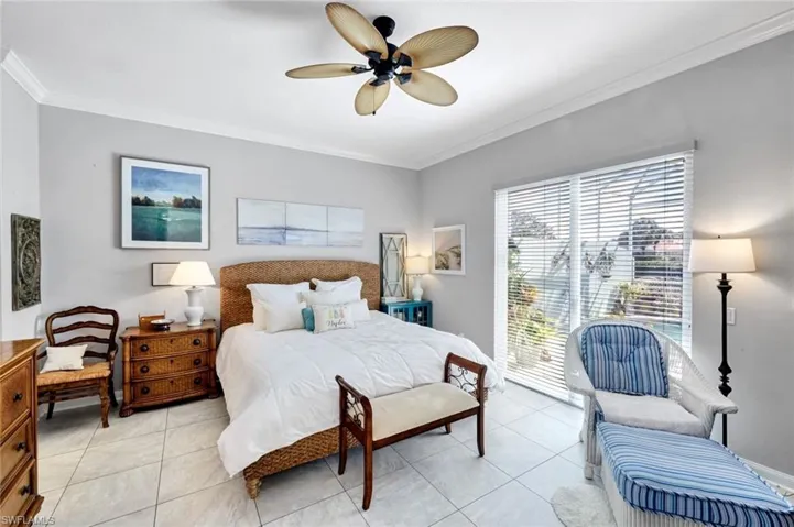 Spacious room featuring light gray walls, crown molding, a ceiling fan with palm-leaf style blades, large format tile flooring, and sliding glass doors with horizontal blinds