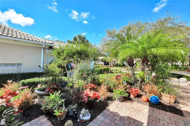 Expansive brick paver patio featuring a mature palm tree and vibrant potted plants