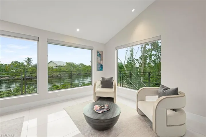 Living area featuring lofted ceiling, a water view, tile patterned floors, and recessed lighting