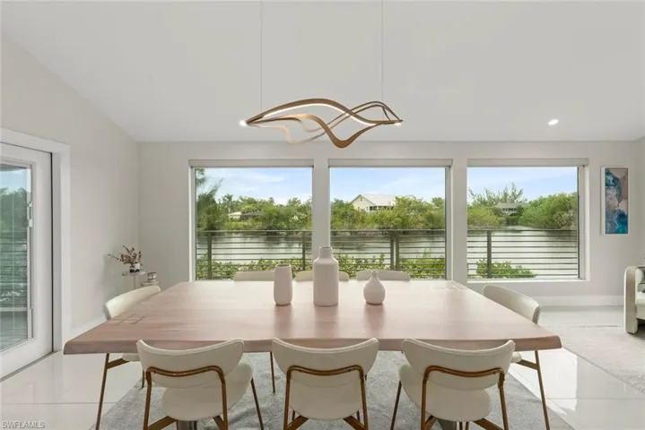 Dining room featuring light tile patterned flooring, a water view, and vaulted ceiling