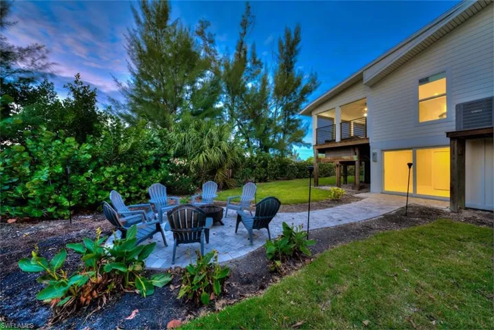 Yard at dusk with a patio, an outdoor fire pit, a yard, and a balcony