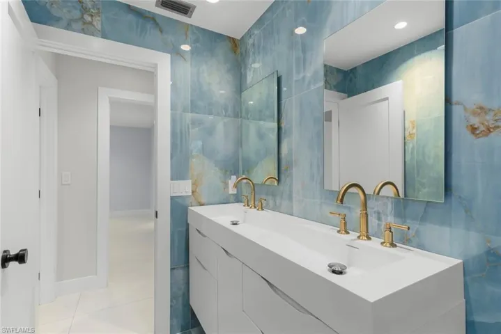Bathroom featuring tile walls, double vanity, and light tile patterned floors