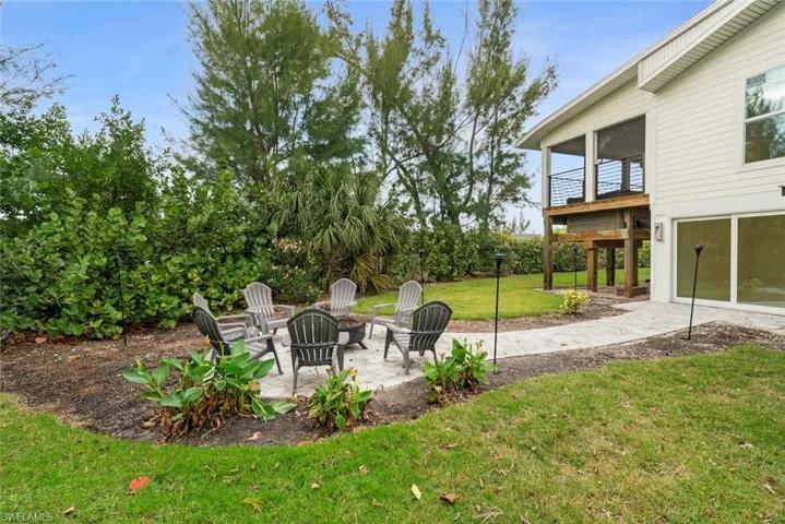 View of grassy yard with a patio area, a sunroom, and a fire pit