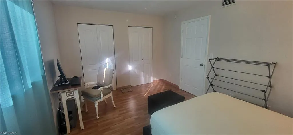 Bedroom with multiple closets and dark wood-type flooring