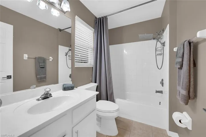 Full bathroom with vanity, toilet, tile patterned floors, and shower / tub combo with curtain