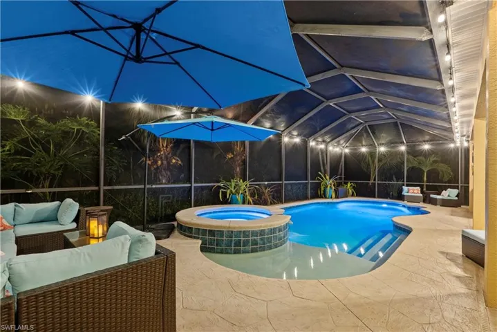 View of swimming pool featuring a patio, a lanai, an outdoor hangout area, and an in ground hot tub