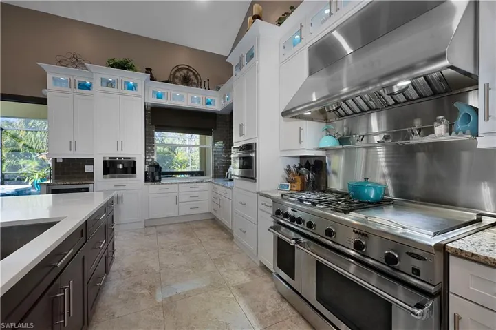 Kitchen featuring tasteful backsplash, stainless steel appliances, extractor fan, and white cabinets