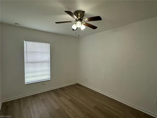 Unfurnished room with dark wood-type flooring and a ceiling fan