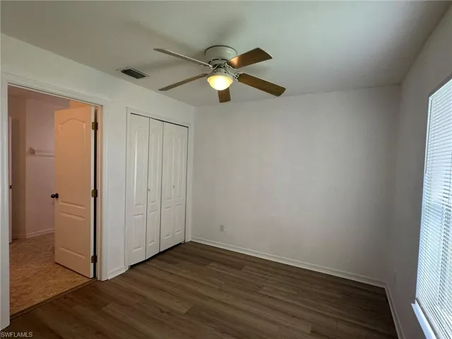 Unfurnished bedroom featuring dark wood-type flooring, a ceiling fan, and a closet