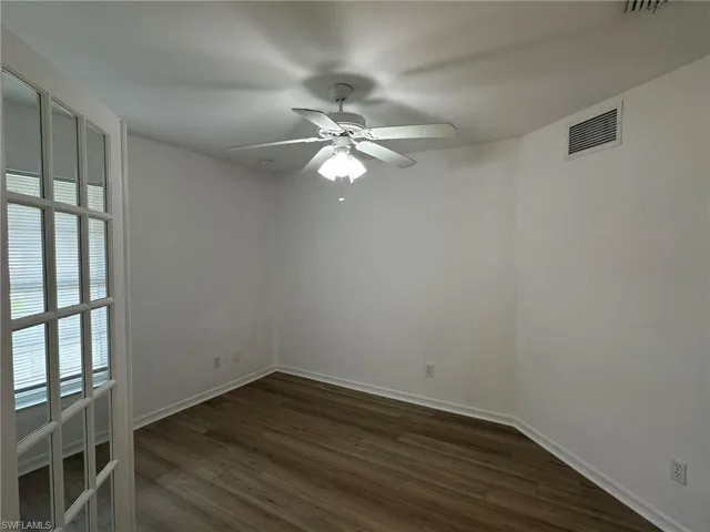 Unfurnished room with dark wood finished floors and a ceiling fan