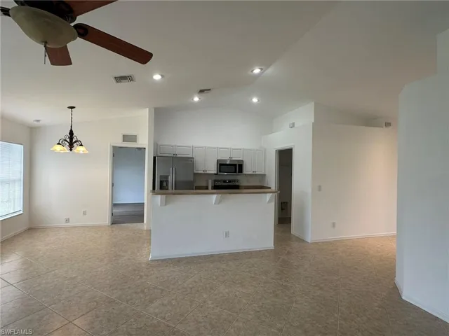 Kitchen featuring open floor plan, appliances with stainless steel finishes, a chandelier, ceiling fan, and high vaulted ceiling