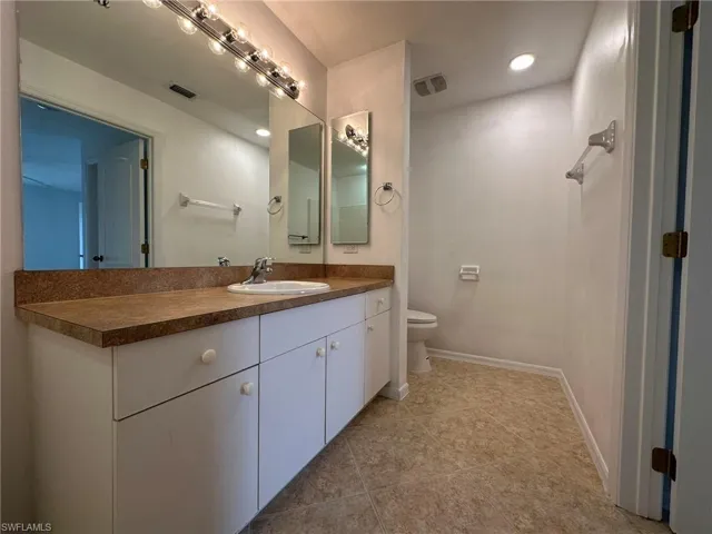 Bathroom with vanity, light tile patterned floors, and recessed lighting