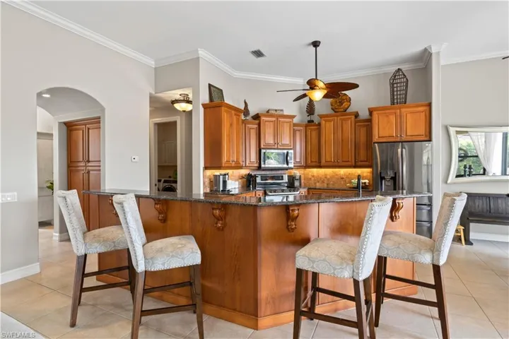 Kitchen with tasteful backsplash, a breakfast bar area, light tile patterned floors, and stainless steel appliances